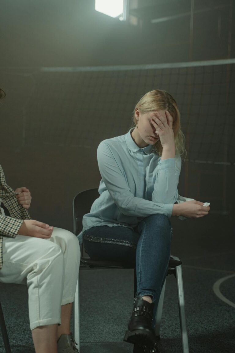 A woman sitting in a support group setting, visibly distressed, highlighting emotional struggles and mental health awareness.